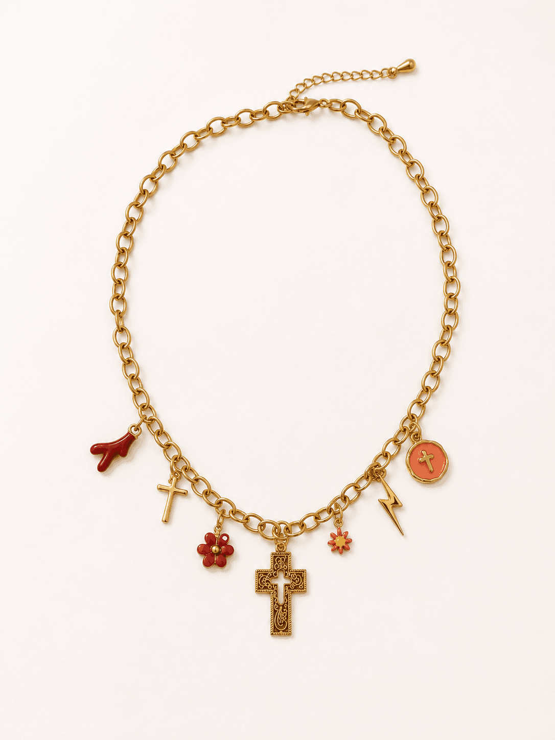 Collier Corallia à plat sur fond blanc, chaîne forçat d'or et 7 pendentifs visibles — brin de corail rouge, petite croix, fleur rouge, crucifix byzantin ciselé, fleur rouge, éclair d'or, médaillon orange émaillé