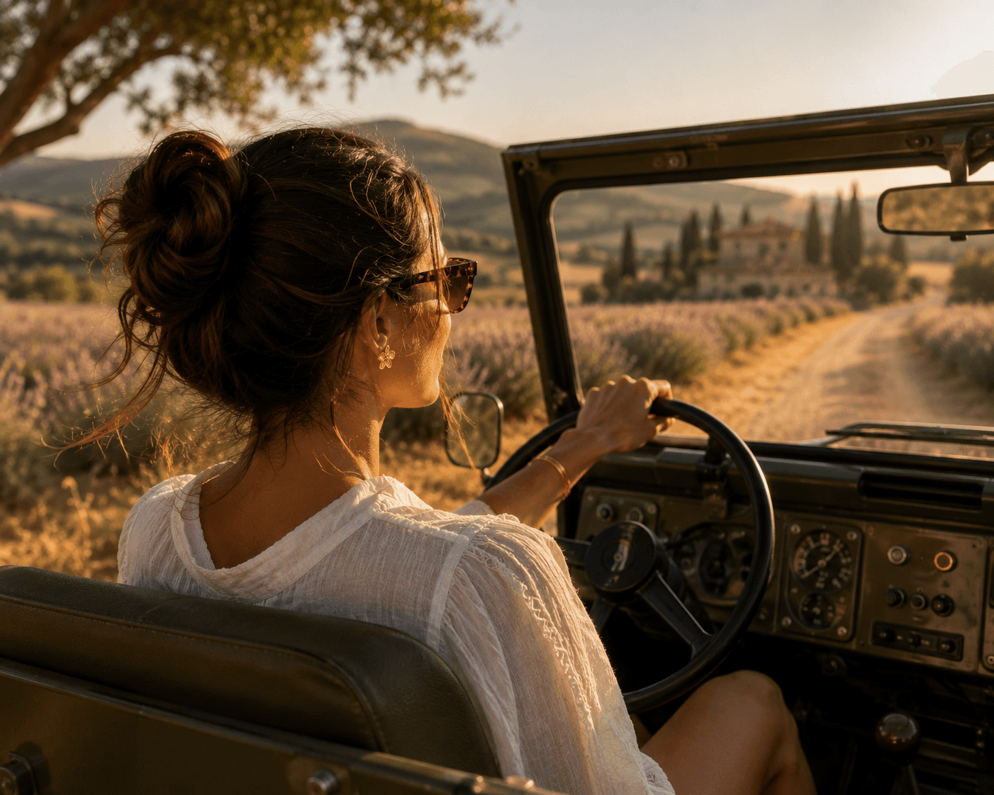 Femme de dos au volant d'un Land Rover vintage, chignon flou et lunettes en écaille, traversant un champ de lavande de Toscane au coucher du soleil, villa et cyprès à l'horizon