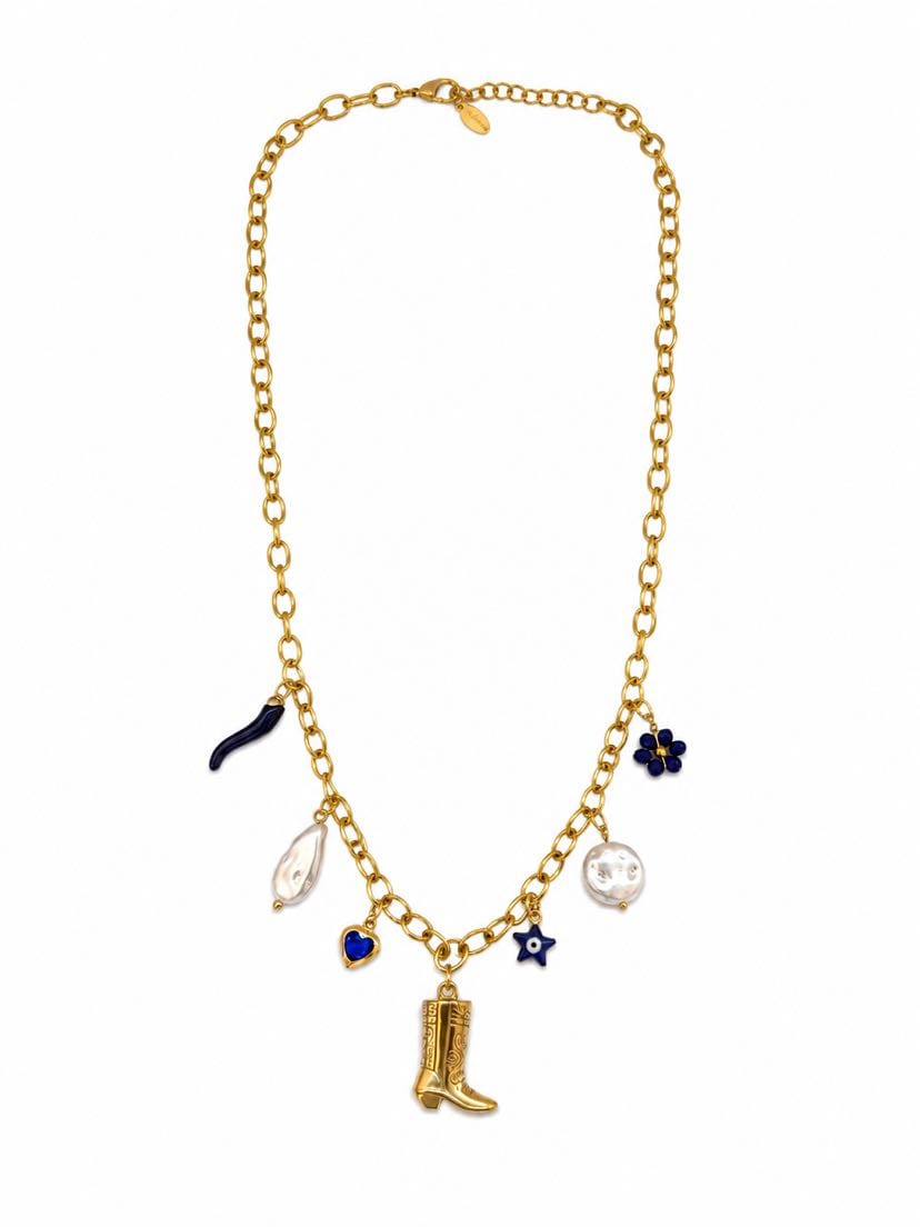 Collier Camargue à plat sur fond crème, chaîne forçat d'or et 7 pendentifs : botte de cowboy d'or ciselée centrée, deux grosses perles baroques blanches, cornicello en émail bleu cobalt, cœur émaillé lapis-lazuli, fleur cluster lapis cluster de 5 perles bleues, petite fleur étoile bleue