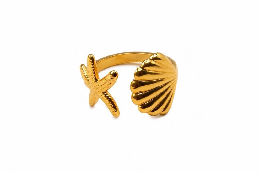 Bague Océline ouverte présentée sur fond blanc d'atelier, vue de profil, anneau or ouvert avec coquille Saint-Jacques à droite et étoile de mer 5 branches à gauche