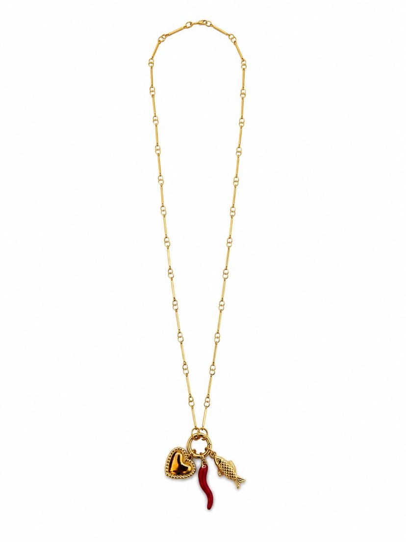 Collier Bella Napoli à plat sur fond crème, chaîne longue à maillons marins alternés, cluster pendentif au bas — cœur d'or bombé, cornicello rouge en émail vitrifié, petit poisson d'or ciselé