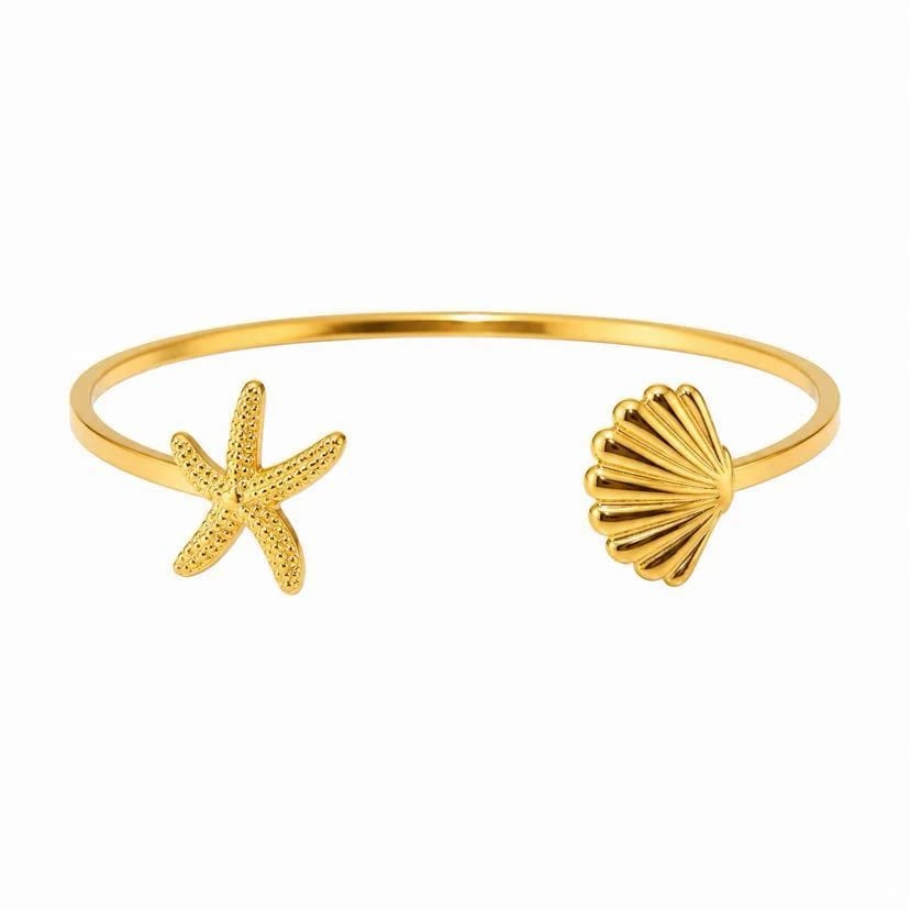 Bracelet jonc Catalina ouvert à plat sur fond blanc studio, fin jonc d'or semi-rigide avec étoile de mer ciselée à une extrémité et coquille Saint-Jacques bombée à l'autre, ouverture latérale visible
